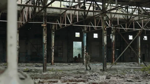 Soldier with machine gun looking around in destroyed factory Stock Footage 203874364