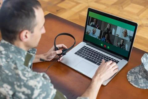 Soldier man smiling while making conference call on laptop indoors Stock Photos