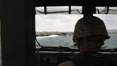 Soldier navigating bridge erection boat behind floating bridge Stock Footage 160106816