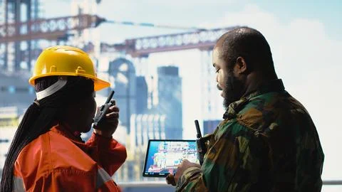 Soldier on offshore platform deck talking with technician, using device Stock Photos