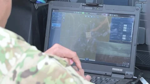 Soldier operates a laptop computer to control an autonomous tactical vehicle Stock Footage 334314465