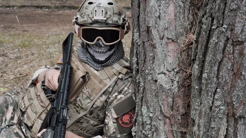 A soldier peeks out from behind a tree. airsoft. 4k Stock Footage 124706321