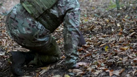 Soldier picking up rifle from forest ground Stock Footage 320770227