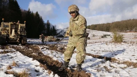Soldier pulls cable from heavy military vehicle Stock Footage 110795667