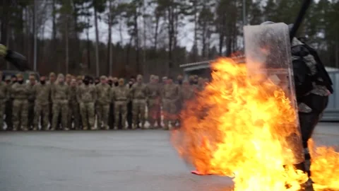 Soldier with riot shield stomping on flames during fire phobia training Stock Footage 264814585