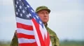 Soldier stand without movement with American flag . Face close up .Slow mo HD Footage