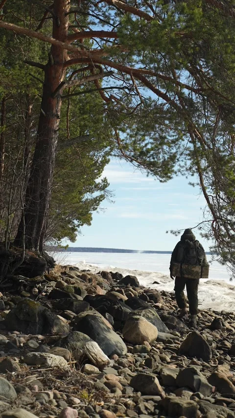 A soldier on a training exercise walks along the shore of a frozen lake. A Video stock 308292049