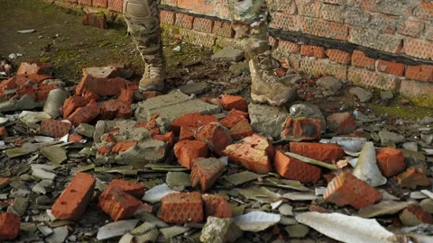 A soldier in uniform and boots walking on the bricks of a destroyed building. Stock-Footage 230226964