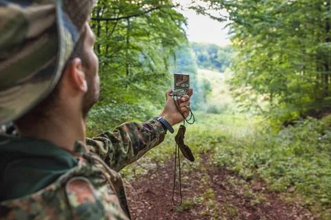 Soldier using compass navigating in forest during operation Stock Photos