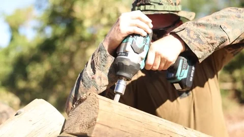 Soldier using drill to insert dowel into wooden pole  Stock Footage 255645426