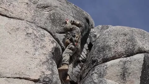 Soldier using rope to ascend rock face  Stock Footage 255117799