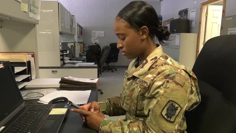 Soldier using smartphone while sitting at desk Stock Footage 94655722