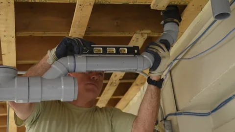 Soldier using spirit level to check alignment of plastic pipes Stock Footage 113394685