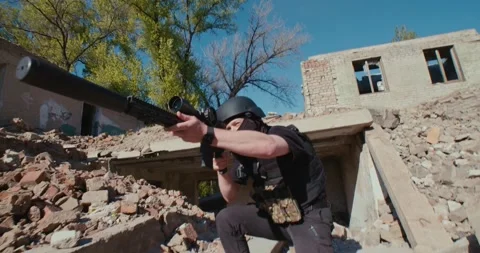 A soldier with a weapon gets out of the destroyed house and shoots Stock Footage 192418696