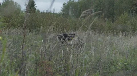 Soldier with weapon in hand goes on the grass. Military moves through the field Stock Footage 68029615