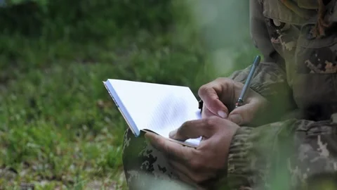 A soldier writes a letter while sitting on the grass. Stock Footage 196417407