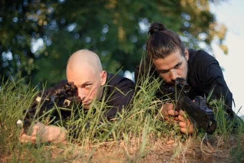 Soldiers aiming down at the target lying hidden n the grass Stock Photos
