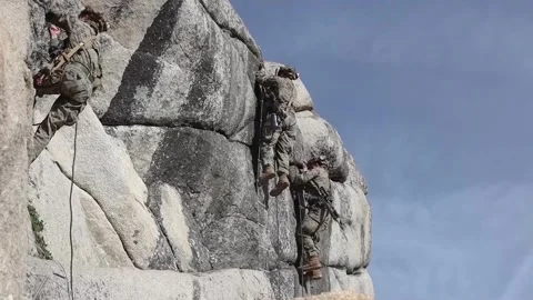 Soldiers ascending rock face using ropes Stock Footage 255117805