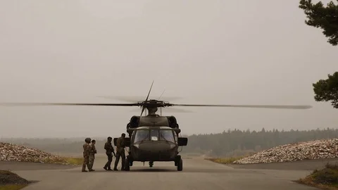 Soldiers boarding a Black Hawk helicopter with rifles Stock Footage 114083976