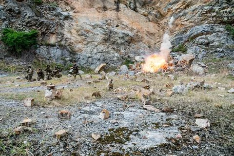 Soldiers conduct explosive training exercise in rocky terrain during daylig.. Foto stock