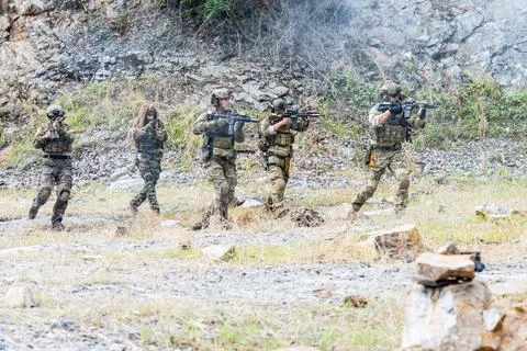 Soldiers conduct training exercise during tactical operation in rocky terrain Stock Photos