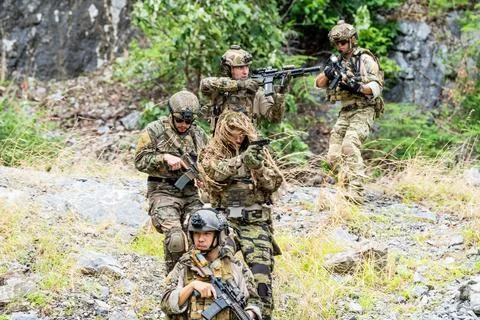 Soldiers engage in tactical training exercise in a wooded area during dayli.. Stock Photos