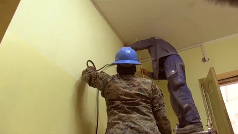 Soldiers installing cable covers on the wall Stock Footage 109575392