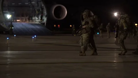 Soldiers march by a Lockheed C-5M Super Galaxy Stock Footage 113346004