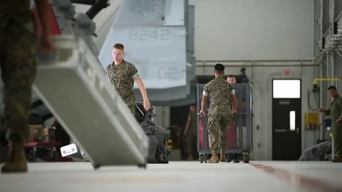 Soldiers pullling trolleys across floor inside hangar Stock Footage 91963251