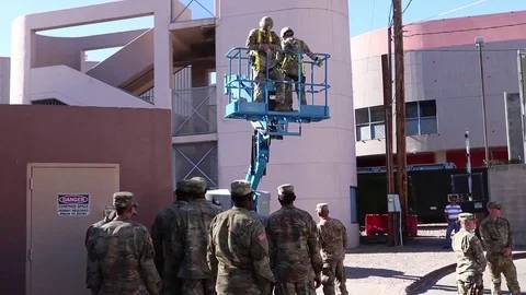 Soldiers ride in mobile platform to secure wire to fence at Mexico border Stock Footage 97979905