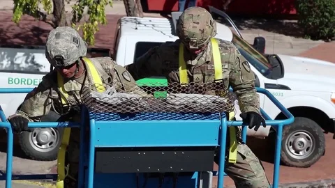 Soldiers ride in mobile platform to secure wire to fence at Mexico border Stock Footage 97979932