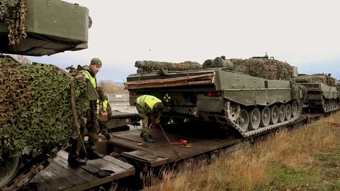 Soldiers secure tanks with camouflage onto a train Stock Footage 110795953