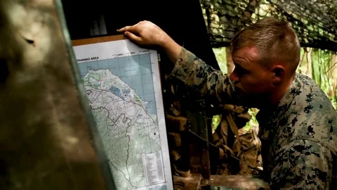 Soldiers studying map plan during jungle patrol Stock Footage 105159857