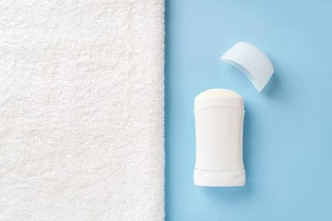 Solid antiperspirant deodorant on a blue background and bath towel. Stock Photos