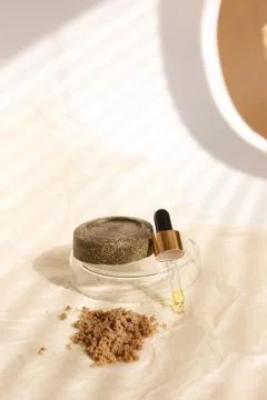 Solid bar of soap and clay powder on plate near pipette , striped shadow 스톡 사진