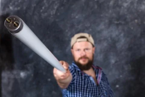 Solid bearded man at casual clothes with a fluorescent lamp looks like stick Stock Photos