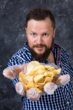 Solid bearded man at casual clothes with heap of chips Foto stock