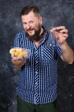 Solid bearded man at casual clothes with heap of chips in one hand and chemical Foto stock