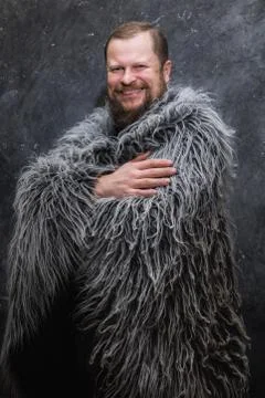 Solid bearded man in a fur skin Stock Photos