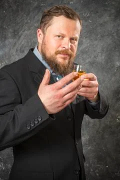 Solid bearded man in suit tasting whisky in a glass Stock Photos