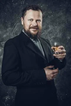 Solid bearded man in suit tasting whisky in a glass Stock Photos