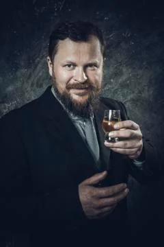 Solid bearded man in suit tasting whisky in a glass Stock Photos