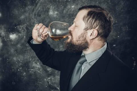 Solid bearded man in suit tasting whisky in a glass Foto stock