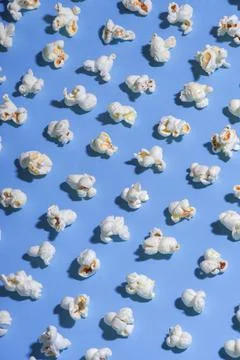 Solid blue background with white popcorn lined up in diagonal rows minimal st 库存照片