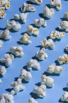 Solid blue background with white popcorn lined up in diagonal rows minimal st 库存照片
