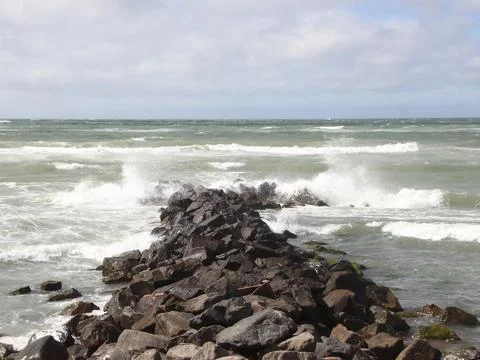 Solid breakwater rocks with cloudy sea horizon Stock Photos