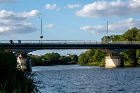 Solid concrete road bridge crossing over a wide peaceful river Foto stock