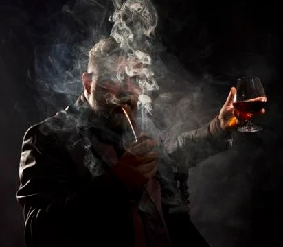 Solid confident bearded man in suit with glass of whisky smoking pipe Stock Photos