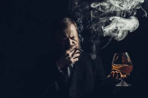 Solid confident bearded man in suit with glass of whisky and cigar with fume Stock Photos