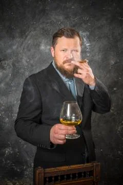 Solid confident bearded man in suit with glass of whisky and cigar Stock Photos